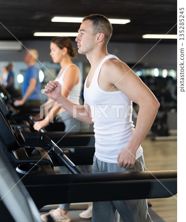 Man walk on treadmill in gym. Active hobby, extensive training Man walk on treadmill in gym. Active hobby, extensive training 135285245