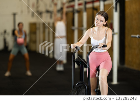 Young woman exercising on exercise bike in gym 135285248