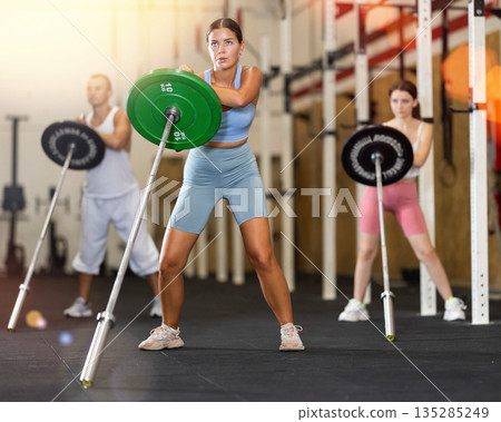 Young woman training with barbell in gym 135285249