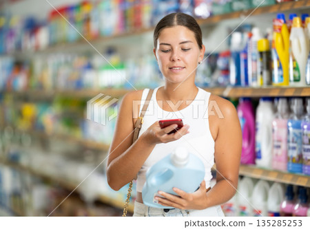 Woman using smartphones to scan barcodes on bottles of alcoholic beverages Woman using smartphones to scan barcodes on bottles of alcoholic beverages 135285253