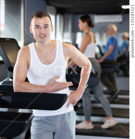Portrait of sporty man against the background of treadmill in gym 135285321