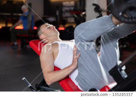 Athlete pulls his legs to his chest on special simulator 135285357