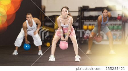 Sporty athletic woman in sportswear training with kettlebell in sport gym Sporty athletic woman in sportswear training with kettlebell in sport gym 135285421