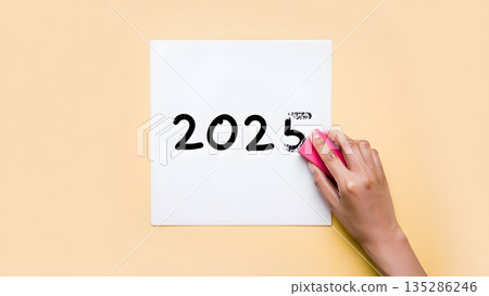 Hand Erasing Year 2025 from White Board on Blush Background 135286246