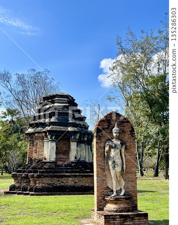 Walking Buddha statue at Wat Trapanggung in Sukhothai Historical Park Walking Buddha statue at Wat Trapanggung in Sukhothai Historical Park 135286303