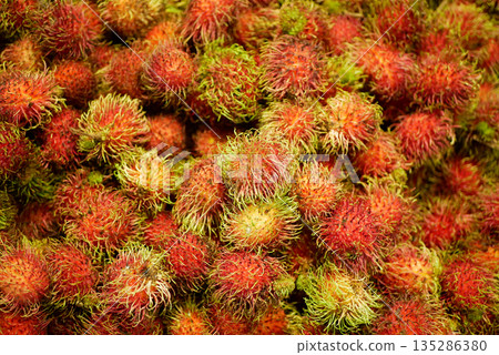 Rambutan Nephelium lappaceum native to Southeast Asia, fruit exotic tropical stall market edible. Round to oval single-seeded drupe, cluster of ten to twenty detail close-up fruits together market 135286380