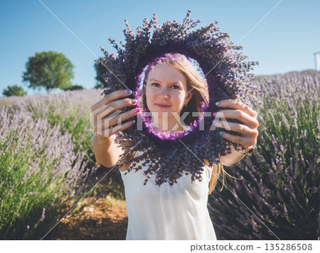 Woman hands with colorful manicure holding lavender wreath 135286508