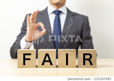 A businessman making an OK pose with a block that says "FAIR" 135287983