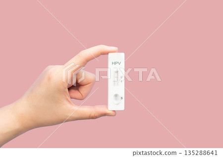 Hand holding HPV test kit for cervical cancer screening on pink background. Screening tool for at home use, that checks for high risk Human Papillomavirus types that can cause cervical cancer. Hand holding HPV test kit for cervical cancer screening on pink background. Screening tool for at home use, that checks for high risk Human Papillomavirus types that can cause cervical cancer. 135288641