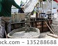 Construction workers are pouring fresh wet concrete into a cement bin to create a strong foundation. 135288688