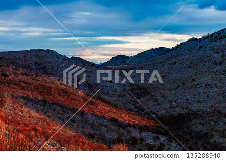 Dramatic Mountain Valley At Dusk With Blue Sky And Red Sunlit Hills 135288940