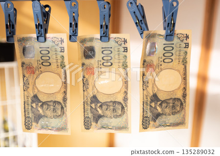 髒兮兮的1000日圓鈔票晾在晾衣繩上。 135289032
