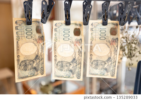 髒兮兮的1000日圓鈔票晾在晾衣繩上。 135289033