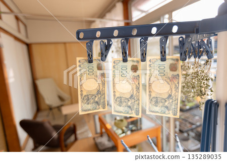 髒兮兮的1000日圓鈔票晾在晾衣繩上。 135289035