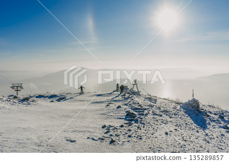 People on a snowy mountain top at Sheregesh ski resort with sun light 135289857