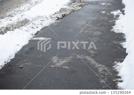 Deicing chemicals on street in winter. Slippery road sprinkled with technical salt. Prevent slipping 135290264