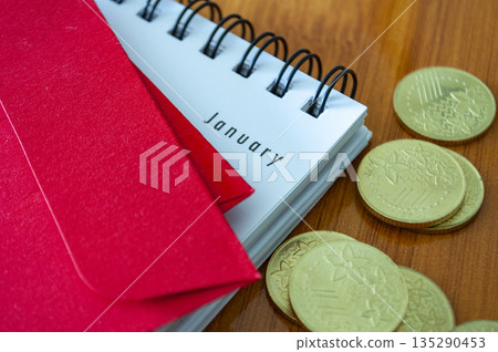Gold coins with notebook with text of January on red background representing planning, wealth, and Lunar New Year preparation. Gold coins with notebook with text of January on red background representing planning, wealth, and Lunar New Year preparation. 135290453
