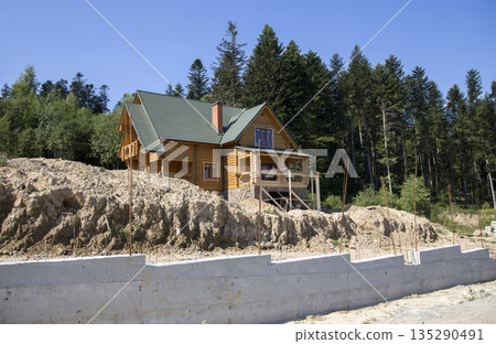 Construction of a wooden cottage in the forest area Construction of a wooden cottage in the forest area 135290491
