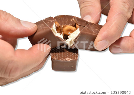 Men's hands break apart a chocolate candy. Men's hands break apart a chocolate candy. 135290943