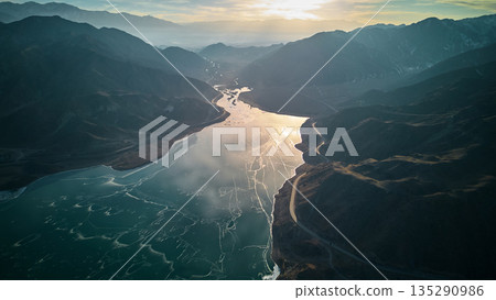 Aerial view of mountain lake with cracked ice reflecting sunset 135290986