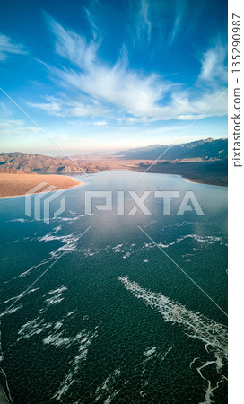 Aerial view of a frozen lake with ice cracks and desert mountains. Winter 135290987