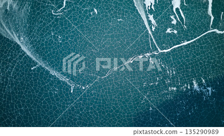 Abstract aerial view of cracked ice on dark blue lake water. Winter Abstract aerial view of cracked ice on dark blue lake water. Winter 135290989