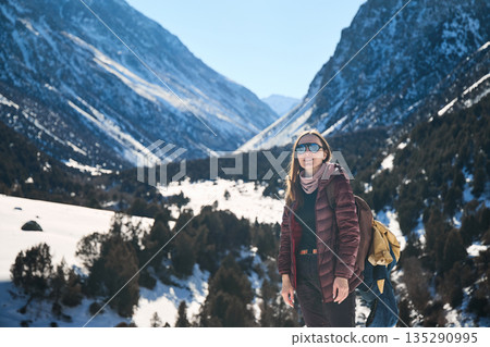 Happy woman adventurer with backpack in snow mountains. Winter hiking and travel Happy woman adventurer with backpack in snow mountains. Winter hiking and travel 135290995