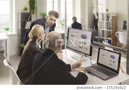 Business team analyzing data charts on screens during office strategy meeting 135291022