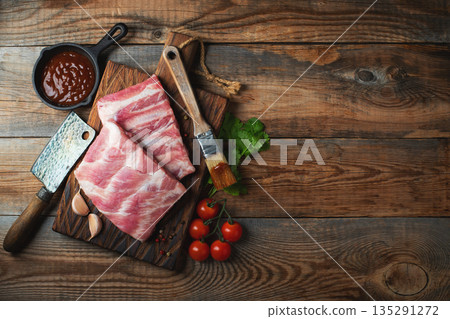Raw pork ribs with spices, salt and rosemary on dark wooden background Raw pork ribs with spices, salt and rosemary on dark wooden background 135291272