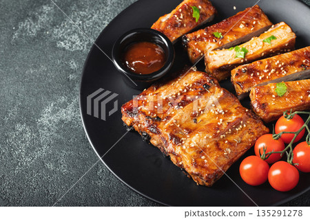 Hot grilled spare ribs from a summer BBQ served on a plate with sauce. Top view. Copy space 135291278