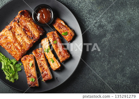 Hot grilled spare ribs from a summer BBQ served on a plate with sauce. Top view. Copy space 135291279