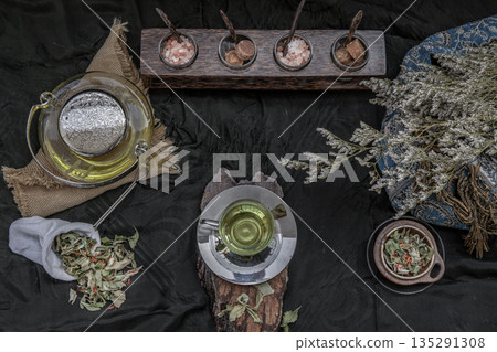 A Beautiful composition with a hot pandan leaf tea with indian marsh fleabane plant leaves and Safflower dried (Saffron substitute) at dark background. 135291308