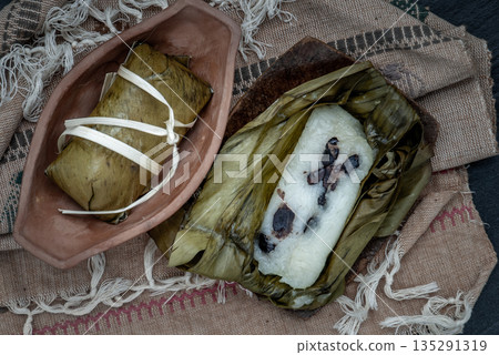 Khao tom mat, a Laotian and Thai dessert of seasoned steamed sticky rice wrapped in banana leaves normally inserted with filling made of banana and black beans for special occasions or merit making. Khao tom mat, a Laotian and Thai dessert of seasoned steamed sticky rice wrapped in banana leaves normally inserted with filling made of banana and black beans for special occasions or merit making. 135291319