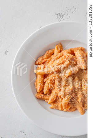 Penne pasta in creamy ricotta tomato sauce with grated parmesan cheese 135291358