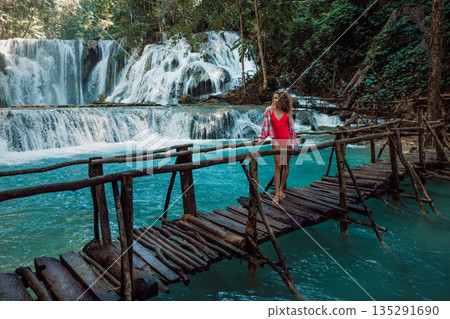 Woman on bridge at cascade waterfalls with turquoise water in Central Sulawesi, Indonesia Woman on bridge at cascade waterfalls with turquoise water in Central Sulawesi, Indonesia 135291690