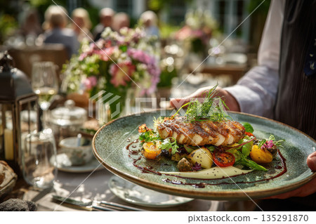 A waiter in a stylish uniform carries a gourmet dish to a guest. Serving at a table in a restaurant. 135291870