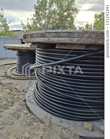 Black electrical cables are being unspooled for installation Black electrical cables are being unspooled for installation 135291941