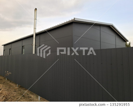 A metal fence and a rural house covered in metal 135291955