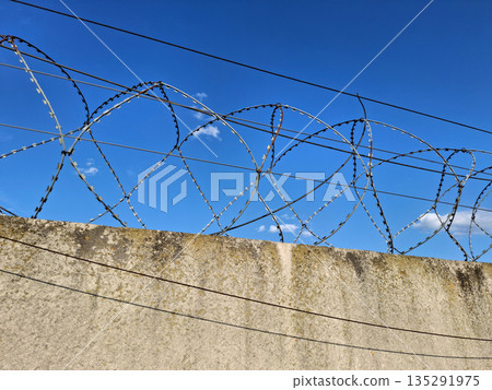 Metal barbed wire on the fence. Forbidden territory, guarded object 135291975