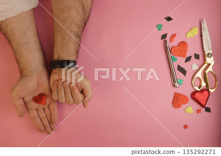 Man holding a secret surprise in a clenched fist next to a small heart 135292271