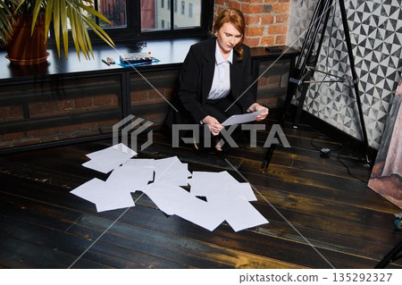 Scene shows investigator studying messy papers in dramatic setting Scene shows investigator studying messy papers in dramatic setting 135292327