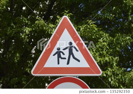 Children on road warning sign with green trees background Children on road warning sign with green trees background 135292350
