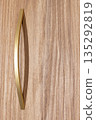 Elegant gold handle rests gently on a textured wooden surface, illuminating minimalist design 135292819
