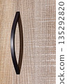 Exploring the elegant curve of a sleek modern handle on textured wooden cabinetry 135292820