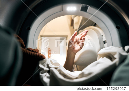 Hand reaching inside washing machine for laundry Hand reaching inside washing machine for laundry 135292917
