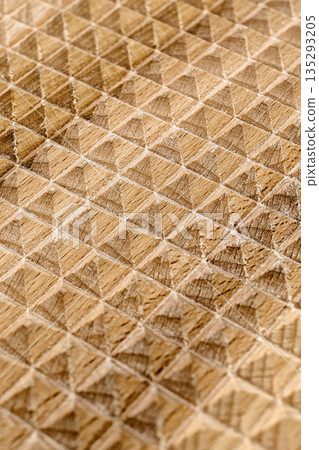 The jagged surface of a flat wooden massager, many small rectangular pyramids, the natural texture and color of the wood The jagged surface of a flat wooden massager, many small rectangular pyramids, the natural texture and color of the wood 135293205