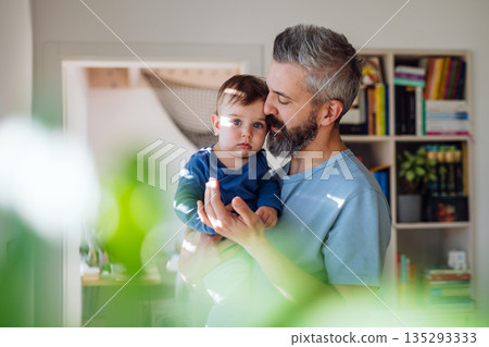 Dad holding his little toddler son in arms. Dad holding his little toddler son in arms. 135293333