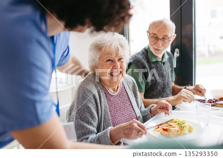 Group of seniors having lunch in community center cafeteria. Group of seniors having lunch in community center cafeteria. 135293350