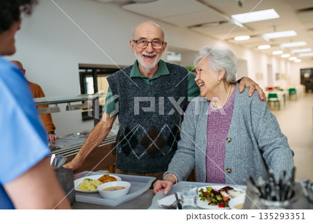 Elderly couple having lunch in community center cafeteria. 135293351