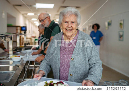 Group of seniors having lunch in community center cafeteria. Group of seniors having lunch in community center cafeteria. 135293352